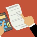 plan for tax season - fingers pointing to calculator and sheet of paper